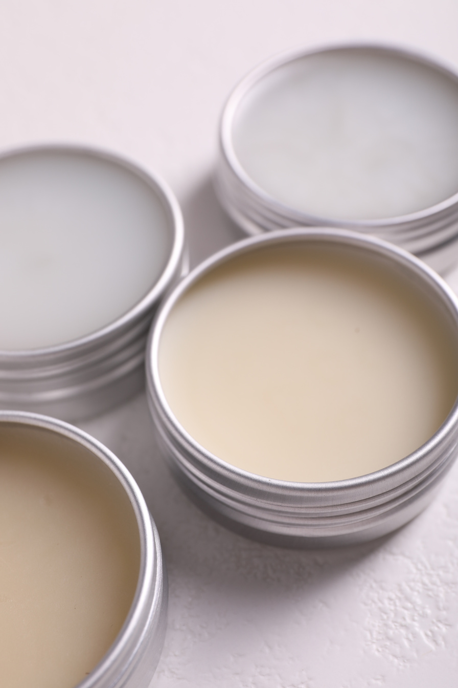 Different Lip Balms on White Table, Closeup